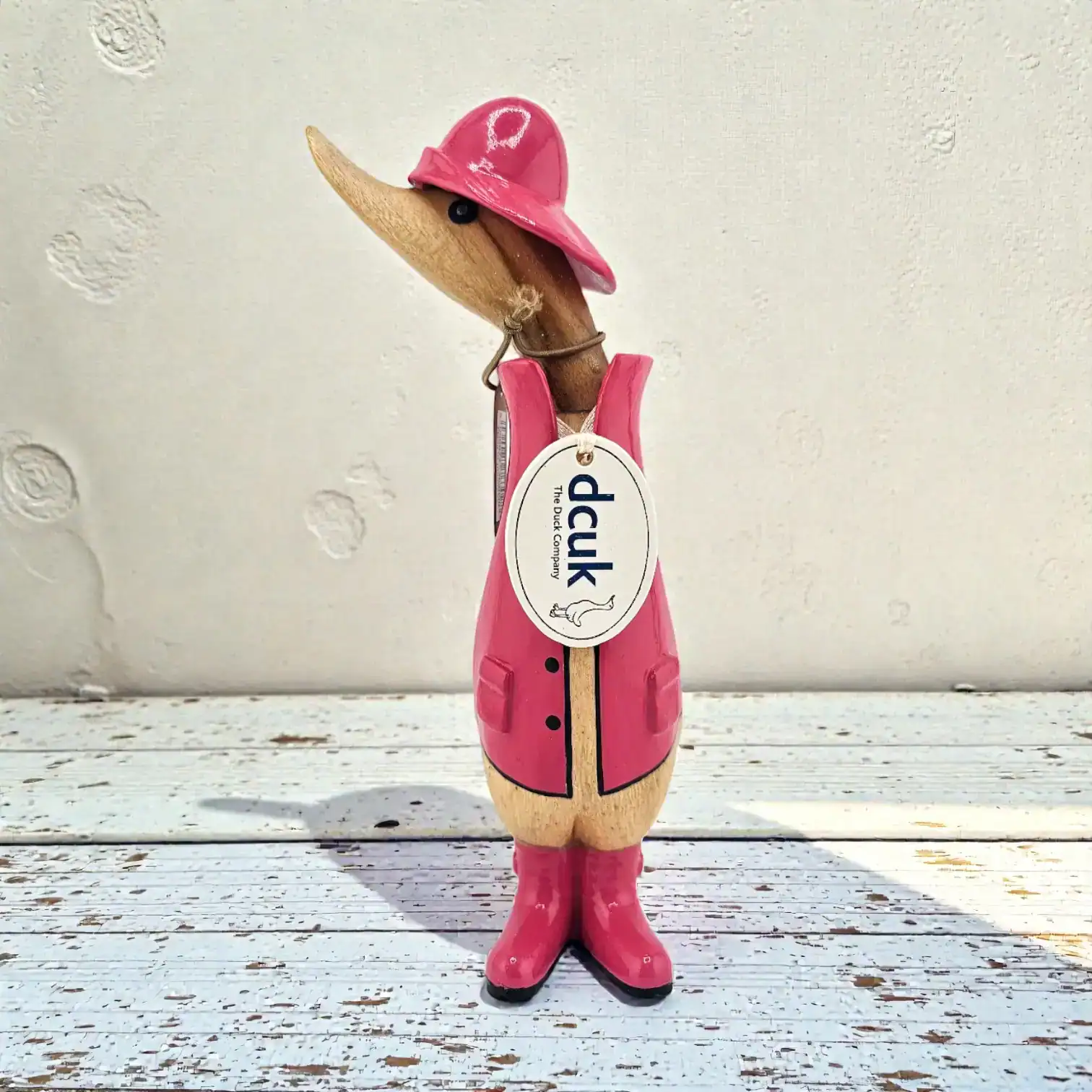 Handcarved bamboo root duck figurine wearing pink raincoat and hat